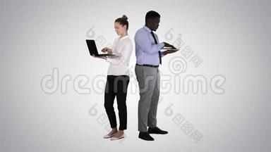 两个背靠背站着，在<strong>渐变背景</strong>下工作在笔记本电脑上。
